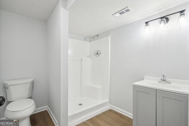 bathroom featuring a shower, hardwood / wood-style floors, vanity, and toilet