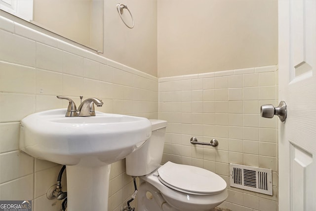 bathroom with toilet and tile walls