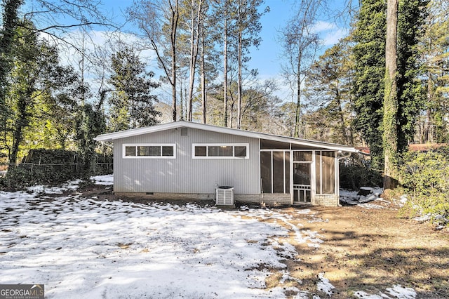 snow covered property featuring cooling unit and a sunroom