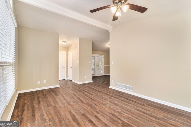 empty room featuring beam ceiling, ceiling fan, a wealth of natural light, and dark hardwood / wood-style floors