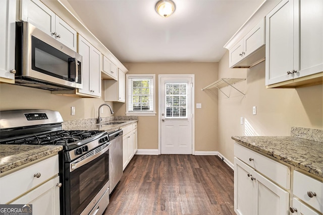 kitchen with light stone counters, stainless steel appliances, dark hardwood / wood-style flooring, white cabinets, and sink