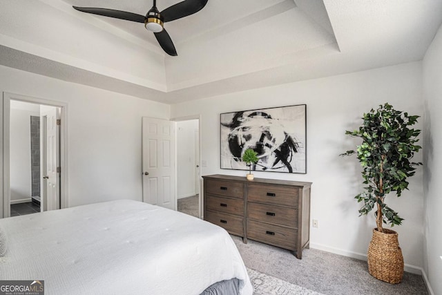 bedroom featuring a high ceiling, a raised ceiling, ceiling fan, connected bathroom, and light colored carpet