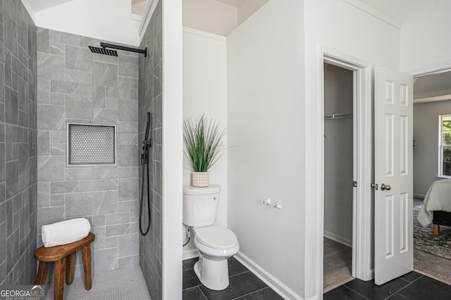 bathroom featuring toilet, tile patterned flooring, and tiled shower