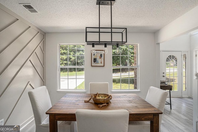 dining area with hardwood / wood-style floors and a textured ceiling