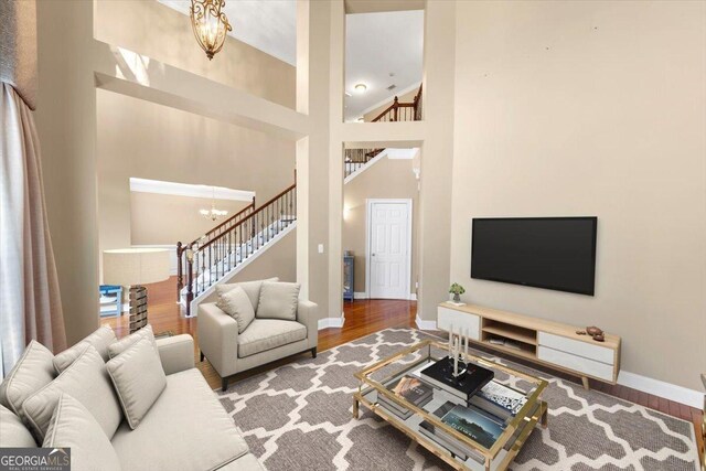 living room with a notable chandelier, hardwood / wood-style floors, and a high ceiling