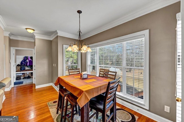 dining area featuring ornamental molding, light hardwood / wood-style floors, and a notable chandelier