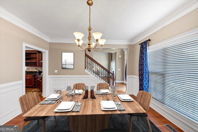 dining area featuring an inviting chandelier, ornamental molding, and hardwood / wood-style flooring