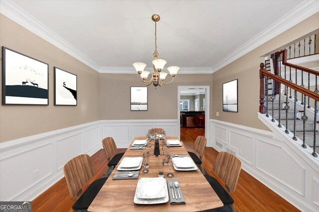 dining space with ornamental molding, hardwood / wood-style floors, and a notable chandelier