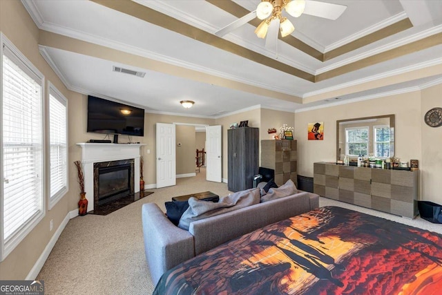 carpeted living room featuring crown molding, ceiling fan, a high end fireplace, and a tray ceiling