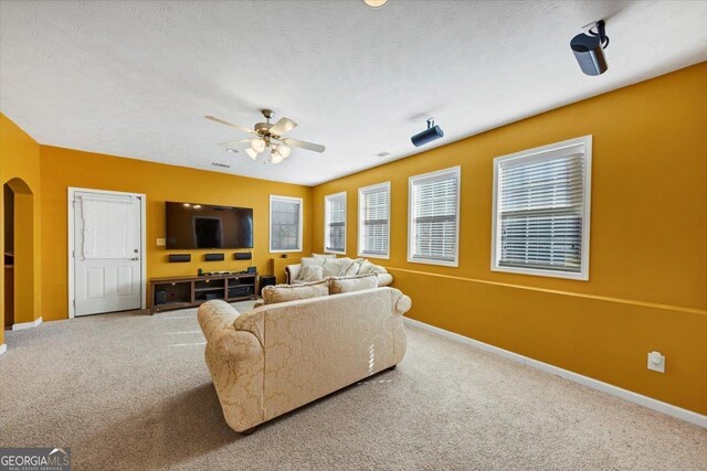 carpeted living room with a textured ceiling and ceiling fan