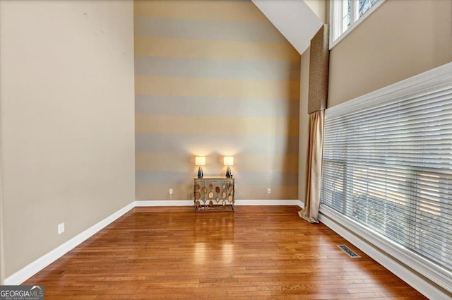 unfurnished room featuring hardwood / wood-style flooring and high vaulted ceiling