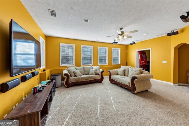 carpeted living room with ceiling fan and a textured ceiling