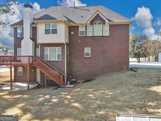 back of property featuring a wooden deck, a yard, and a patio