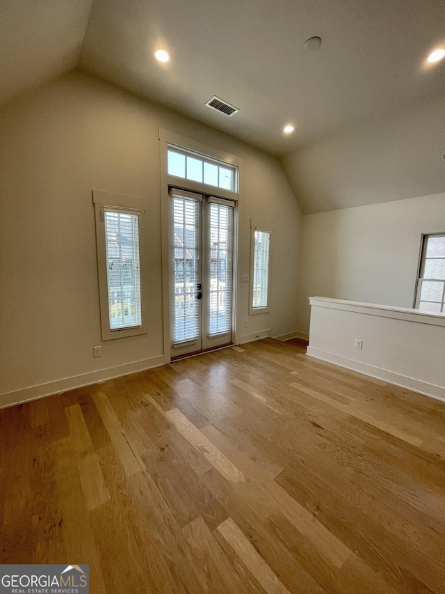 additional living space with french doors, light hardwood / wood-style flooring, and lofted ceiling