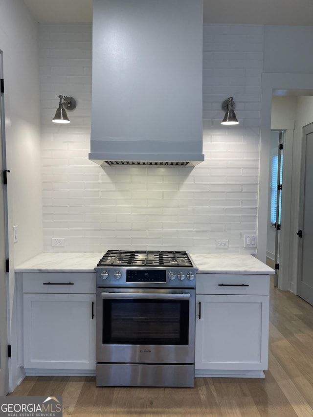 kitchen featuring white cabinetry, stainless steel range with gas cooktop, backsplash, and exhaust hood