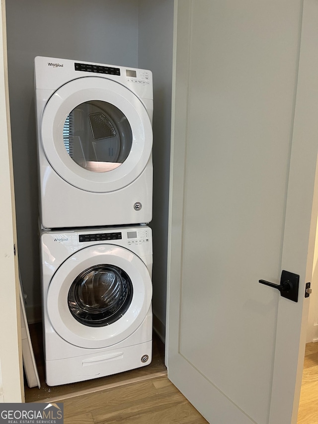 laundry room featuring hardwood / wood-style floors and stacked washer / drying machine