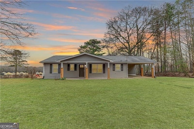 single story home featuring a porch, a carport, and a lawn