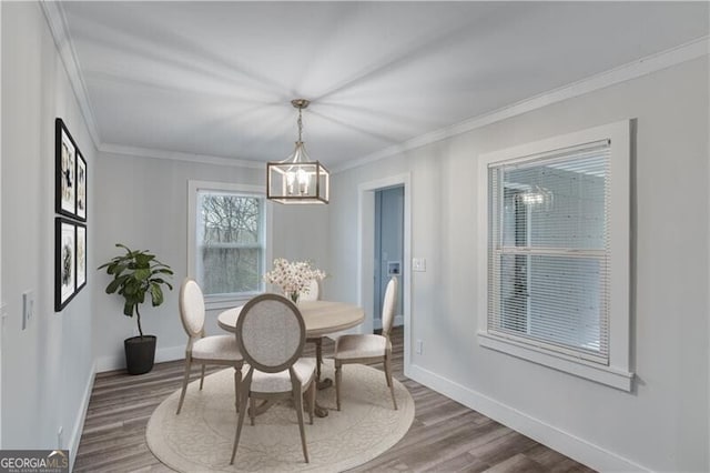 dining room with a notable chandelier, wood-type flooring, and crown molding