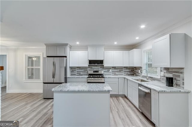 kitchen featuring sink, appliances with stainless steel finishes, tasteful backsplash, a kitchen island, and white cabinetry