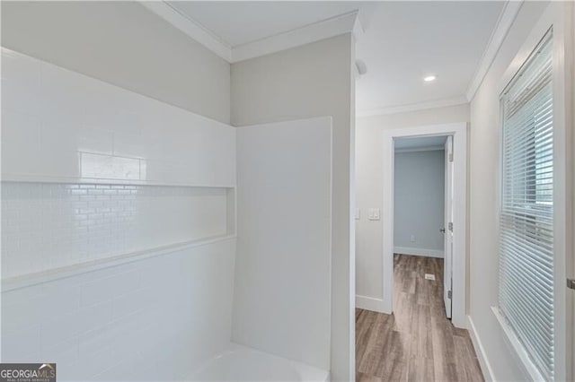 bathroom with wood-type flooring, a tub to relax in, and ornamental molding