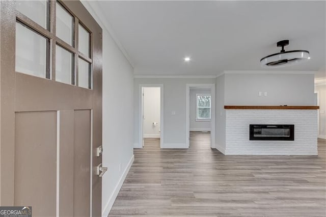 unfurnished living room featuring a fireplace, light hardwood / wood-style floors, and crown molding