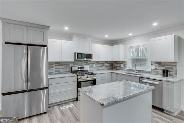 kitchen with light stone countertops, sink, stainless steel appliances, light hardwood / wood-style floors, and a kitchen island