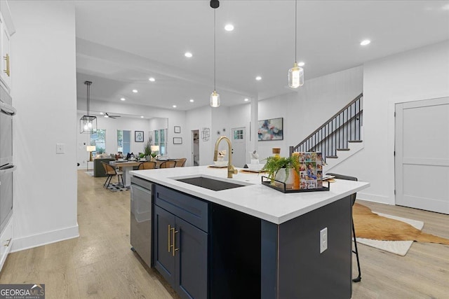 kitchen with a center island with sink, sink, ceiling fan, decorative light fixtures, and a breakfast bar area