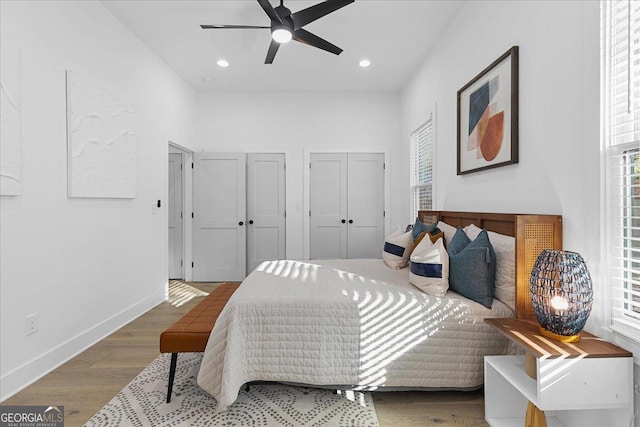 bedroom with ceiling fan, two closets, and hardwood / wood-style flooring