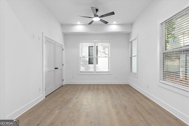 empty room with ceiling fan and light hardwood / wood-style floors