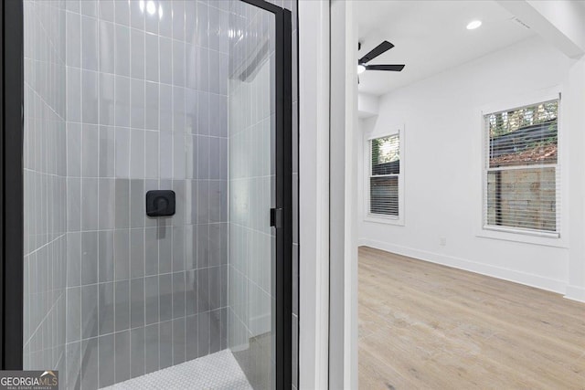 bathroom with ceiling fan, a shower with shower door, and wood-type flooring