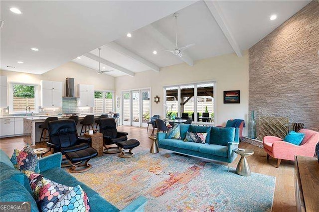 living room featuring vaulted ceiling with beams, ceiling fan, sink, and light hardwood / wood-style floors