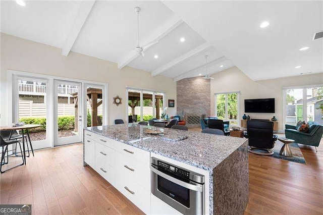 kitchen with a healthy amount of sunlight, white cabinets, lofted ceiling with beams, and a kitchen island