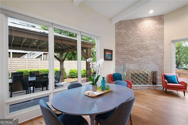 dining room featuring beamed ceiling, wood-type flooring, and high vaulted ceiling