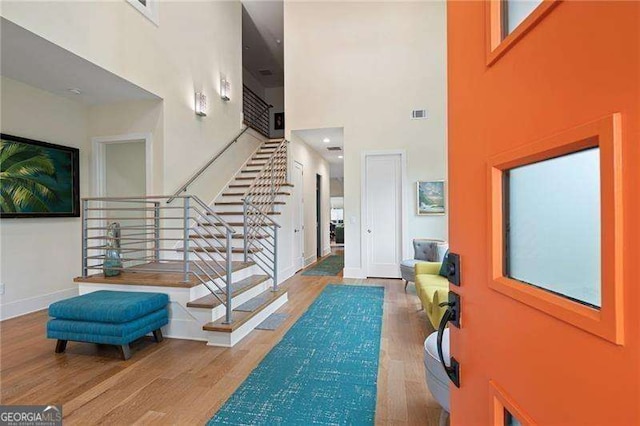 entrance foyer with wood-type flooring and a towering ceiling