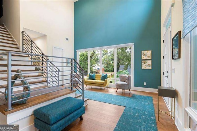 sitting room with a high ceiling and wood-type flooring