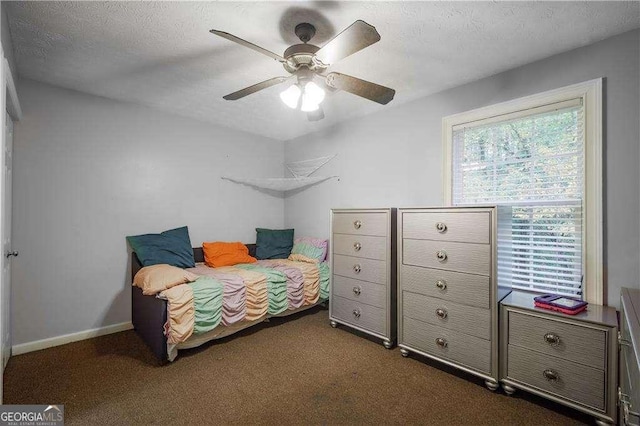 bedroom with a textured ceiling, dark carpet, and ceiling fan