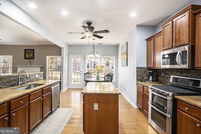 kitchen with sink, light hardwood / wood-style flooring, appliances with stainless steel finishes, a center island, and decorative backsplash