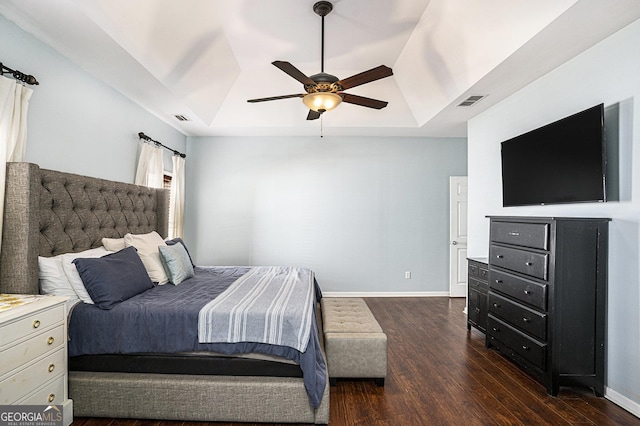 bedroom with a raised ceiling, dark hardwood / wood-style flooring, and ceiling fan