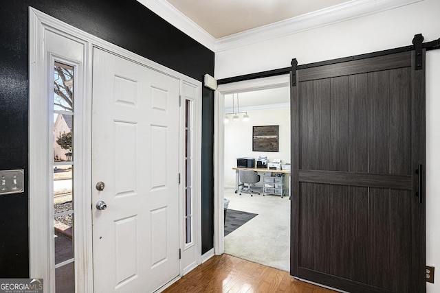 foyer entrance with ornamental molding, a barn door, hardwood / wood-style floors, and a notable chandelier