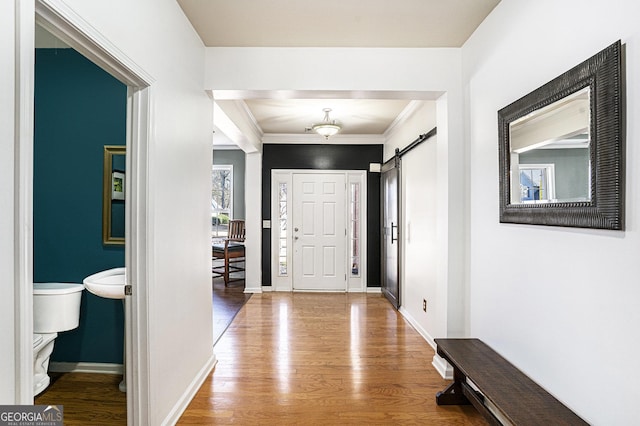 foyer entrance with hardwood / wood-style flooring, a barn door, and crown molding