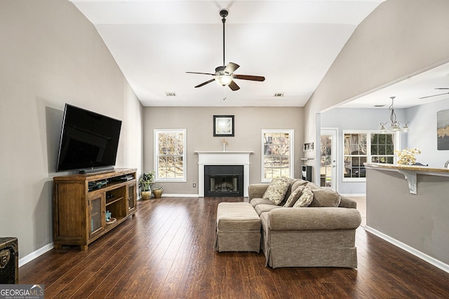 living room featuring vaulted ceiling, dark wood-type flooring, and ceiling fan with notable chandelier