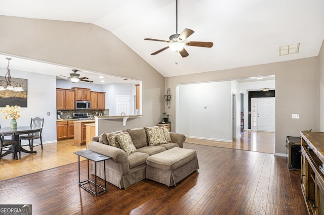 living room with hardwood / wood-style flooring, lofted ceiling, and ceiling fan with notable chandelier