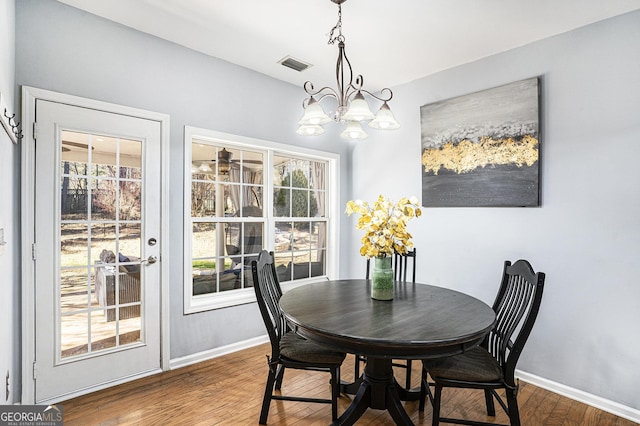 dining space featuring wood-type flooring and a chandelier