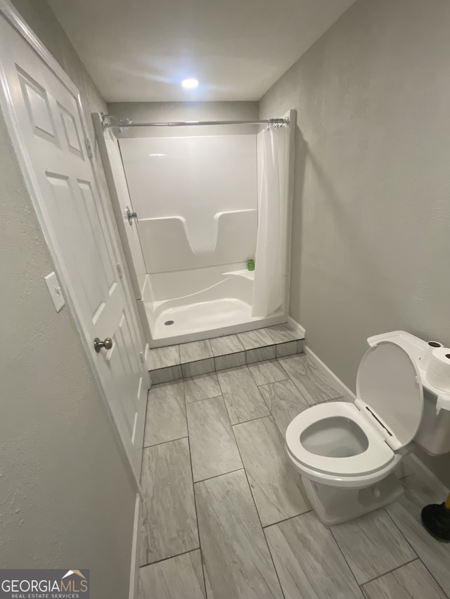 bathroom featuring a shower with shower curtain and toilet