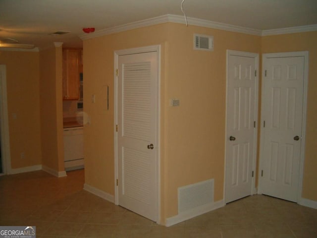 unfurnished bedroom with light tile patterned floors, two closets, and crown molding