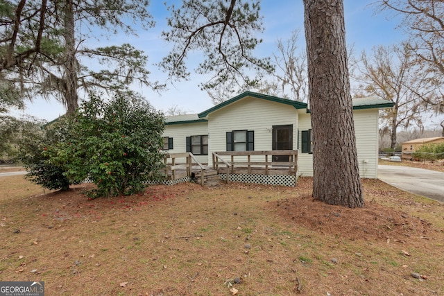 view of front of property with a deck and a front lawn