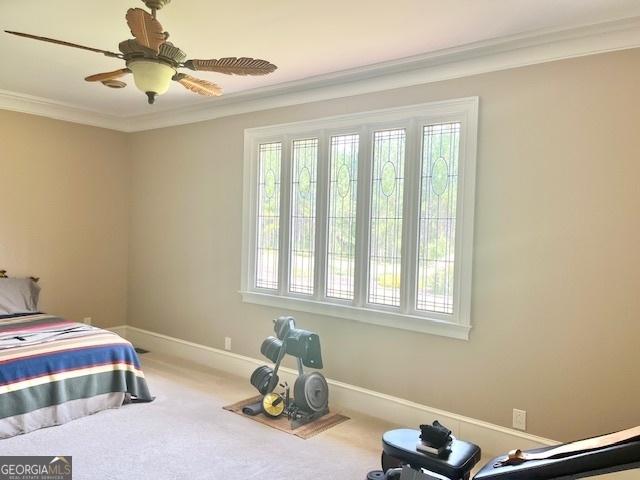 carpeted bedroom with ceiling fan and ornamental molding