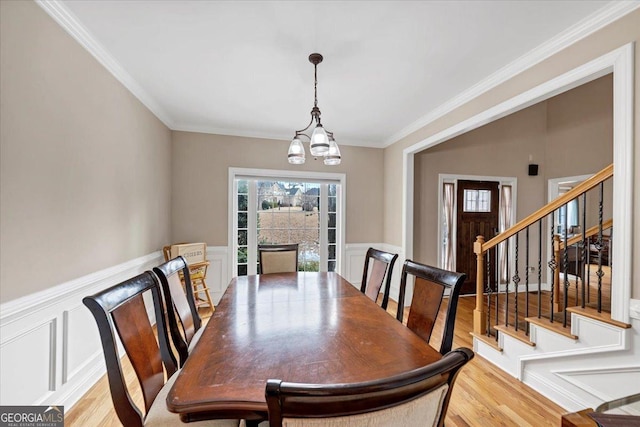 dining room with light hardwood / wood-style floors, ornamental molding, and a chandelier