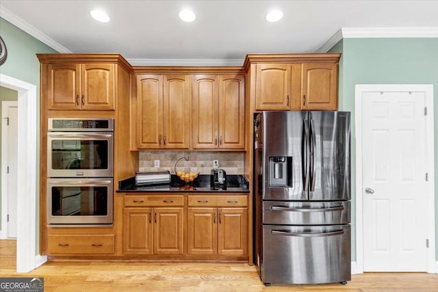 kitchen featuring light wood-type flooring, tasteful backsplash, dark stone counters, stainless steel appliances, and crown molding