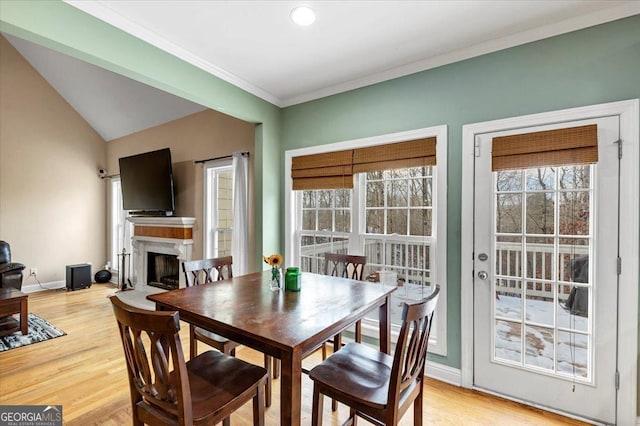 dining area with light wood-type flooring, vaulted ceiling, and crown molding